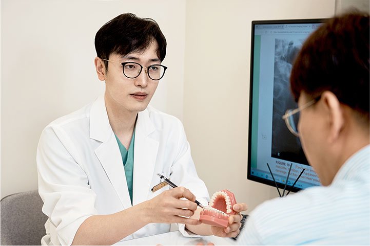 A dentist and a patient looking at intraoral photographs on a monitor.